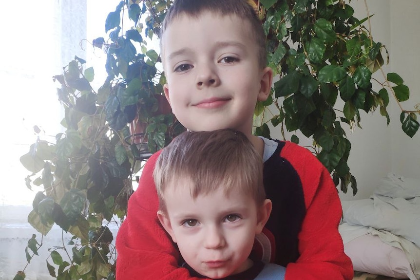 Olga Oryniak's two sons hugging each other and smiling. 