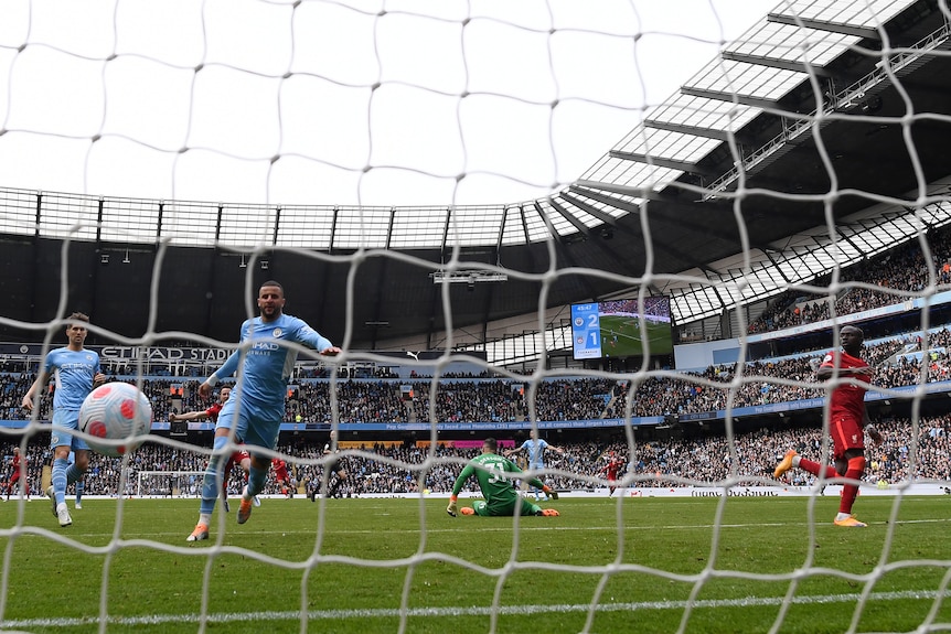 The ball bounces over the line as a defender runs in and the striker wheels around to celebrate the goal. 