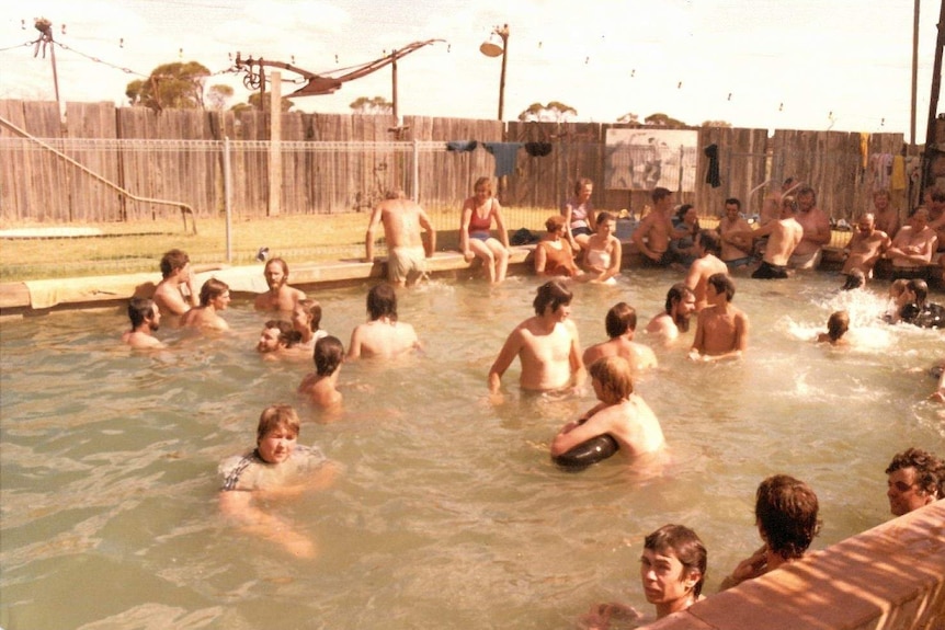 A swimming pool full of people on a social summer weekend.