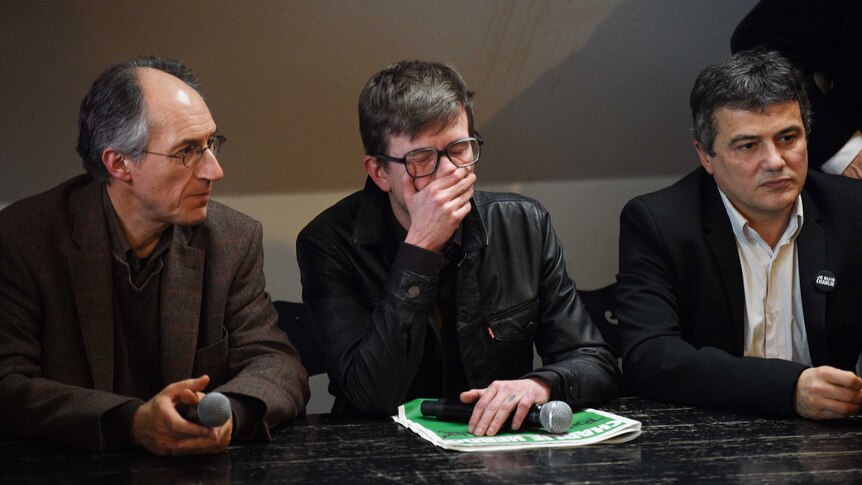 French cartoonist Renald Luzier, centre, cries during a press conference