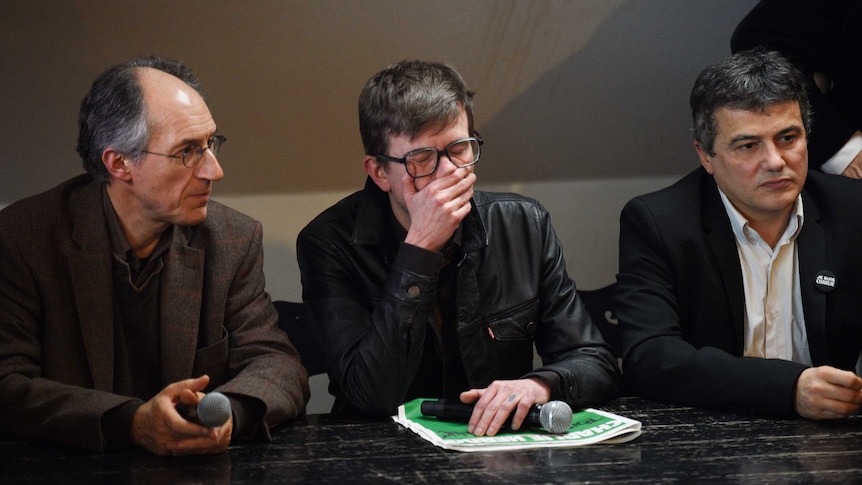 French cartoonist Renald Luzier, centre, cries during a press conference