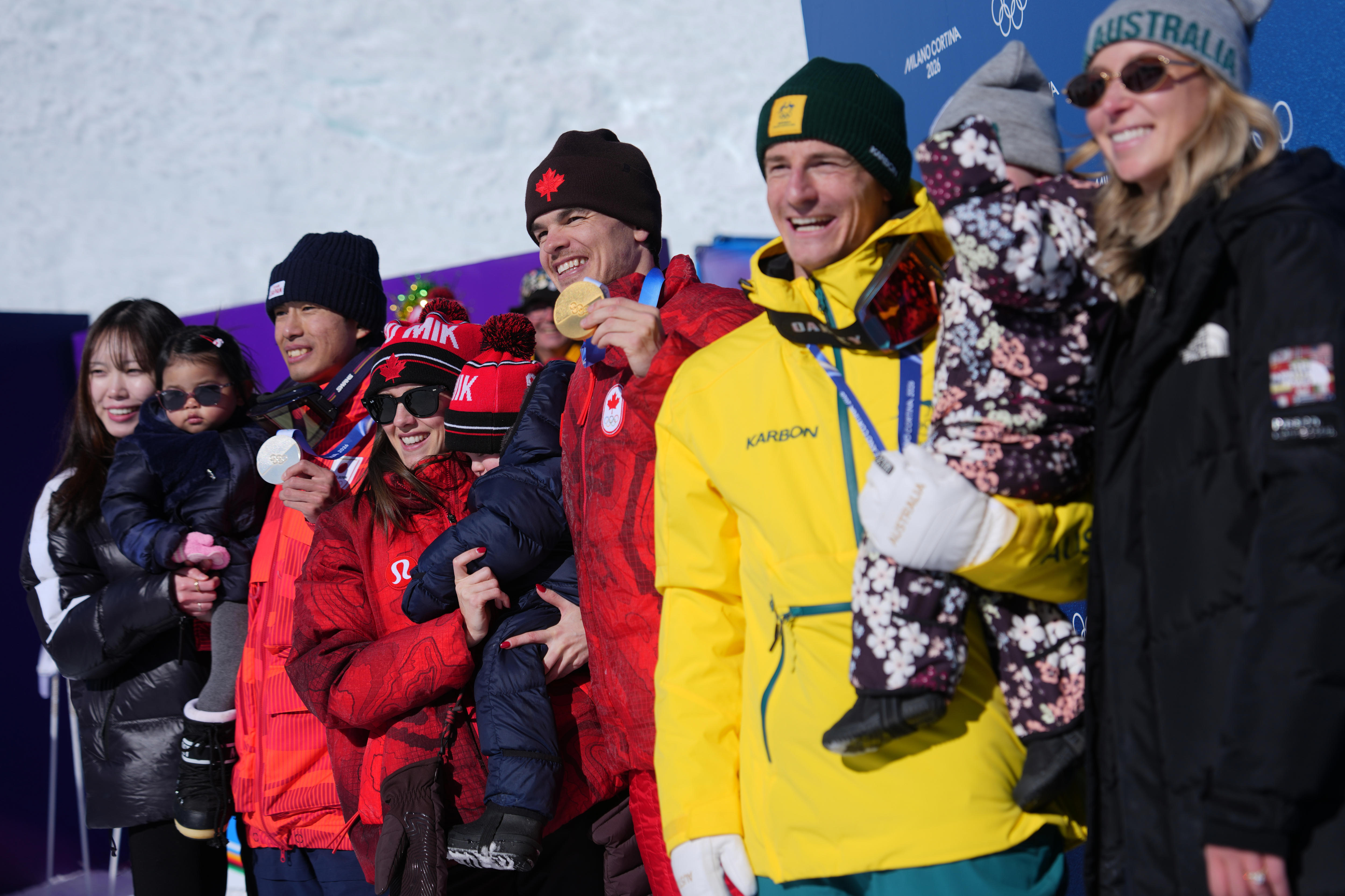 Men's dual moguls medal winners with their children and partners at Milano Cortina.
