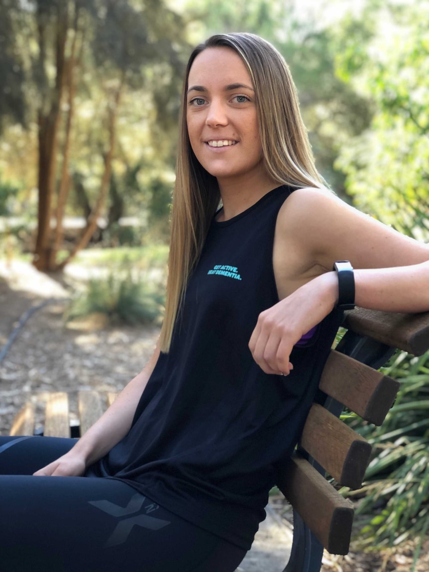 Madi Salter of Adelaide sits on a bench with a smile on her face