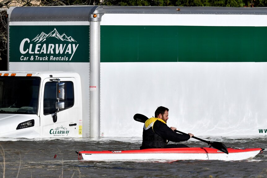 A paddler kayaks past a submerged truck