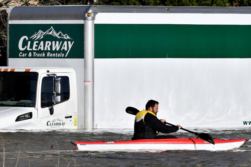 Un pagayeur passe devant un camion submergé en kayak