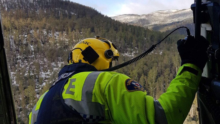 Police officer looks out from a search and rescue helicopter