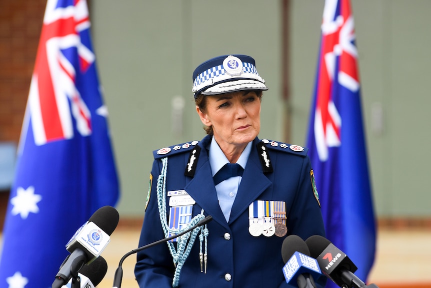 La commissaire Karen Webb en tenue de police officielle devant les drapeaux australiens