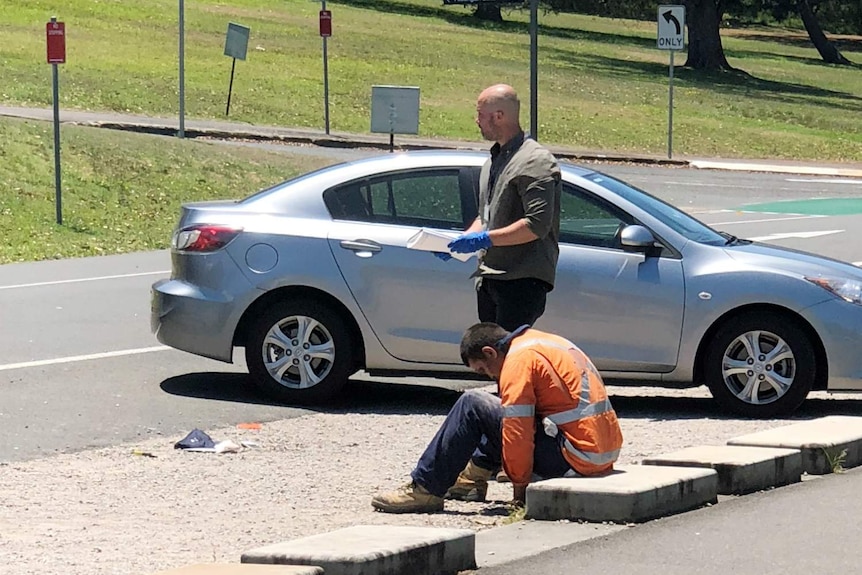 A man on the ground, with another man standing nearby