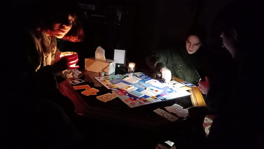 A family plays monopoly by torchlight in a power outage. 