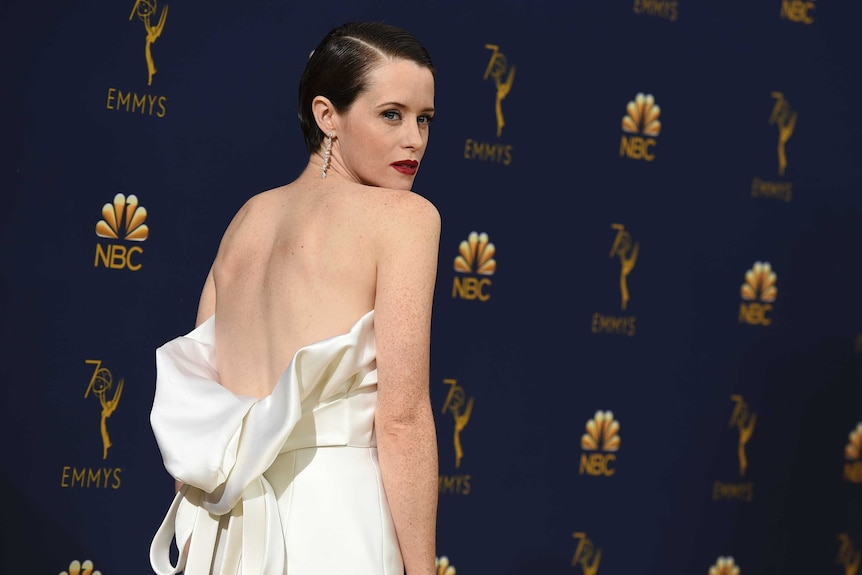 Claire Foy in a white dress, looking over her shoulder.
