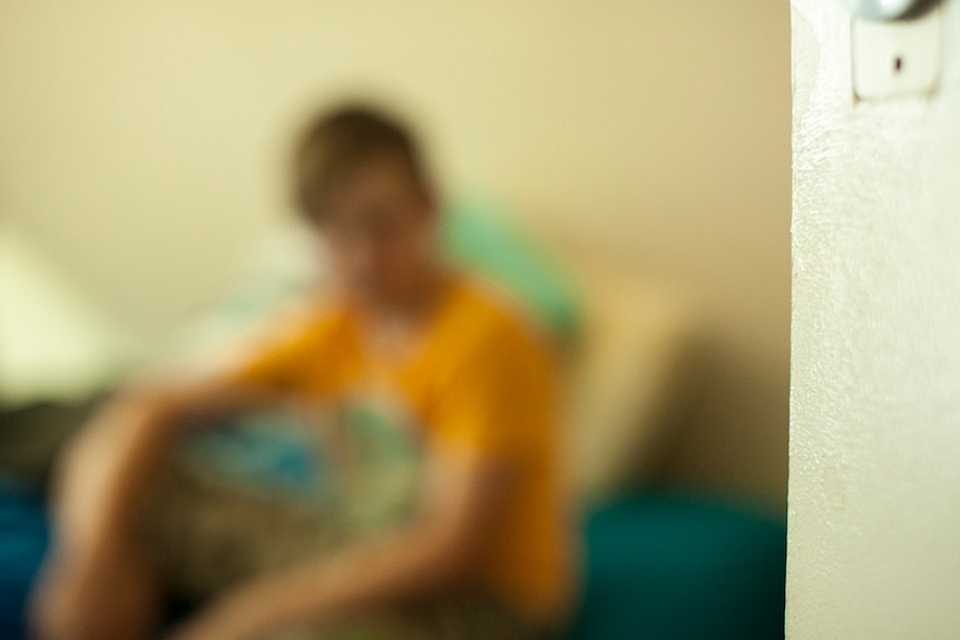 A blurry image of a young boy sitting in his bed bedroom.