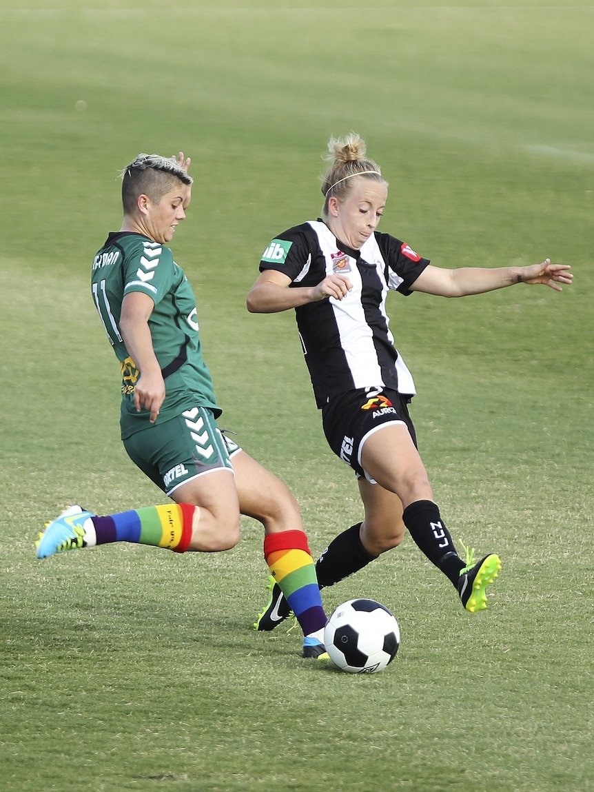 Two female soccer players contest the ball