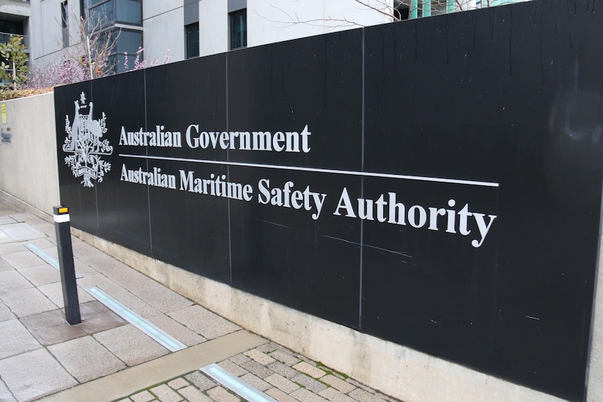 A black sign on a concrete wall that reads 'Australian Government. Australian Maritime Safety Authority'.