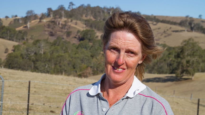 Sharon Walker standing on her property with a burnt out paddock in the background