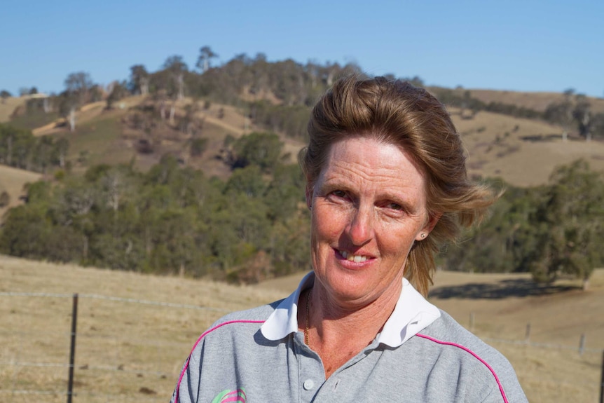 Sharon Walker standing on her property with a burnt out paddock in the background