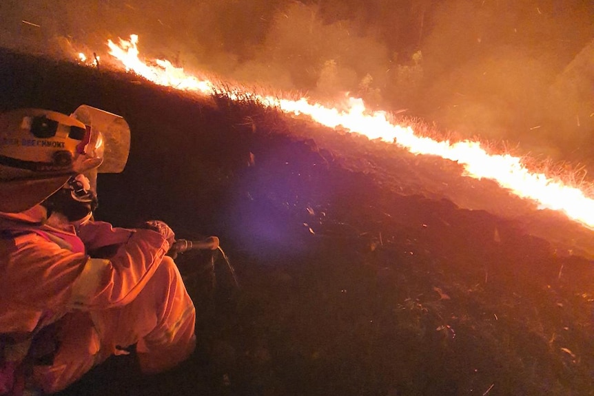 Firefighter sitting in front of small bushfire.
