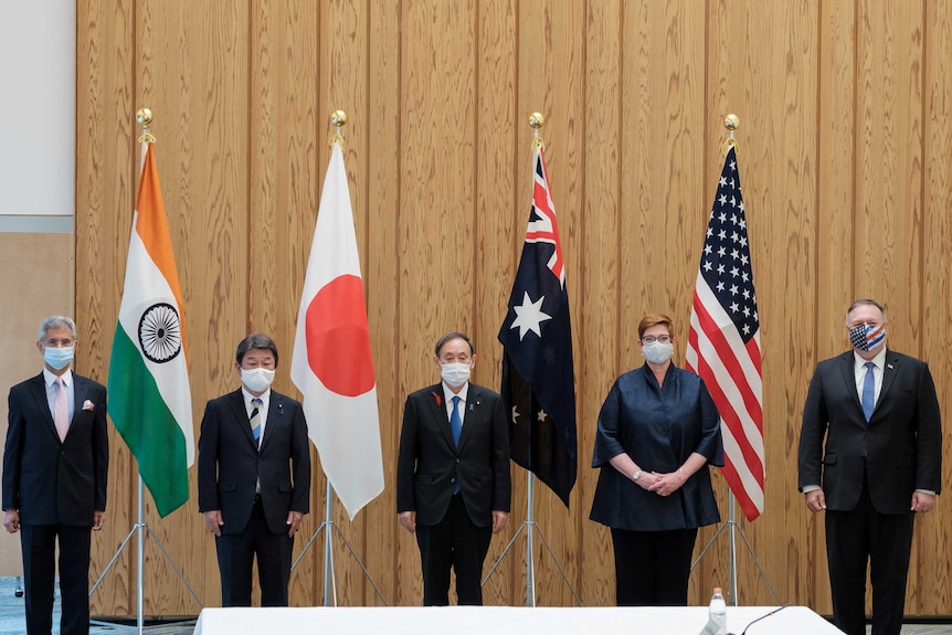 The five members of the Quad, and the Japanese PM, standing in a row behind their respective flags