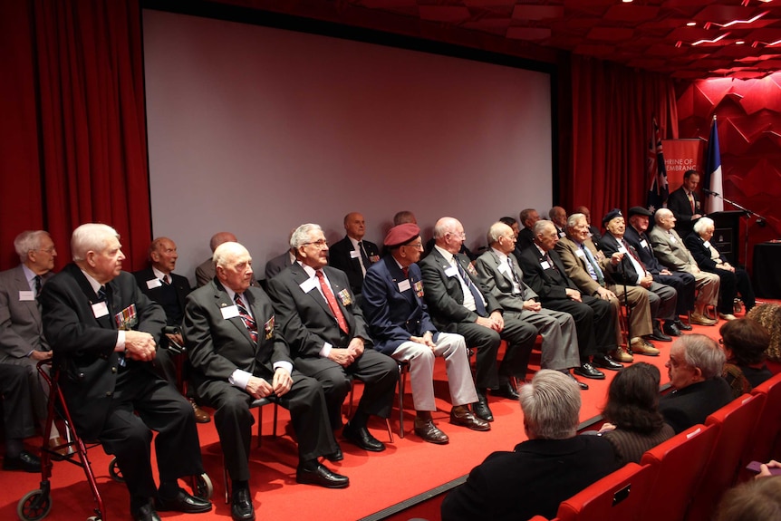 Twenty-six veterans seated and about to receive their Legion of Honour medals at Melbourne's Shrine of Remembrance.