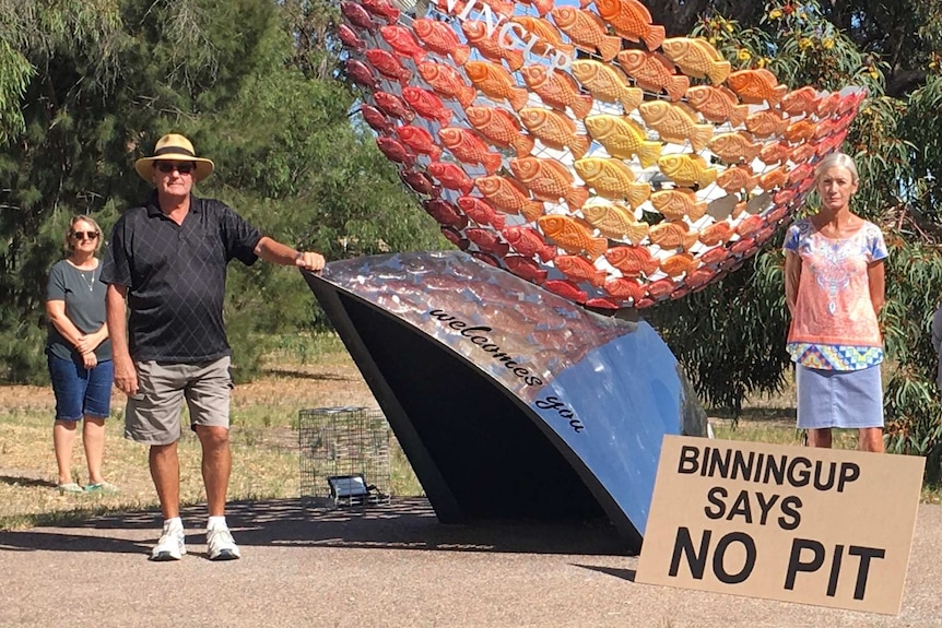 two women and a man standing apart, in front of the Binningup entrance with a sign that says 'Binningup says no pit".