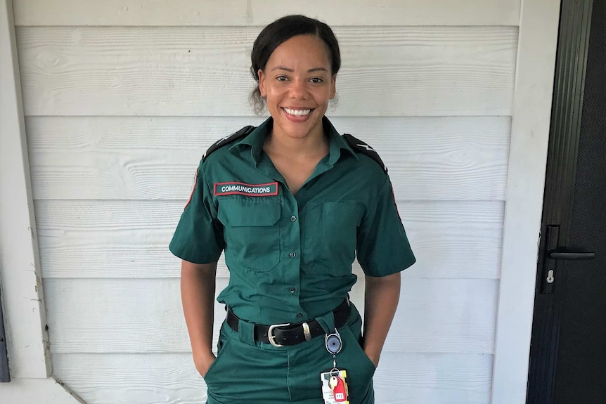 A woman standing hands in pocket in St John Ambulance uniform against a white wall.