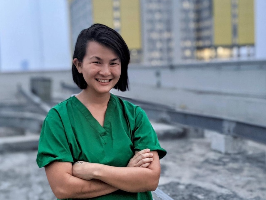 A photo of Dr Lumanauw  wearing green scrubs, crossing her arms.