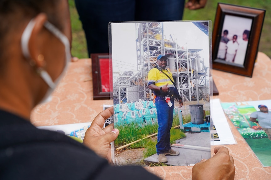 A woman holds a picture of a man 