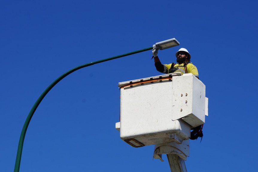 worker changing street light to LED