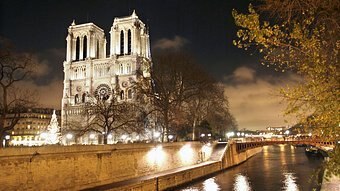 Notre Dame is seen before the fire, lit up at night beside the Seine