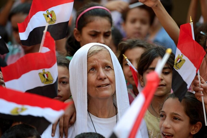 Mama Maggie Gobran surrounded by children holding Egyptian flags.