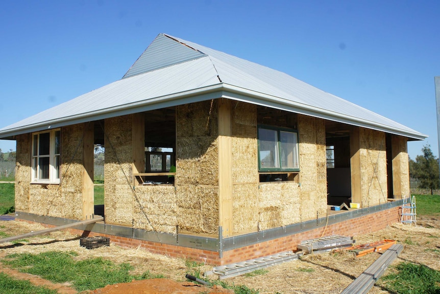 A straw bale house under construction showing the bales and frame