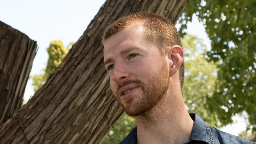 A man with a beard in front of a tree