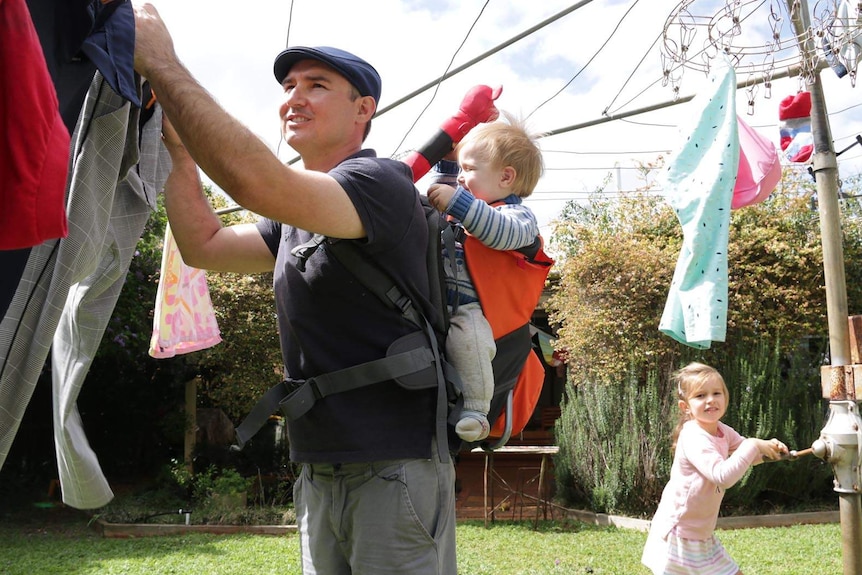 A man hanging washing with his children