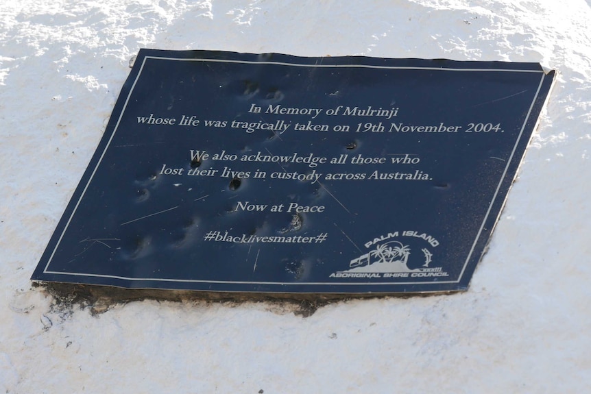 A plaque on a white rock has dents and scratches