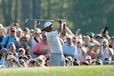 Tiger Woods watches a shot at Augusta, while a large crowd watches on