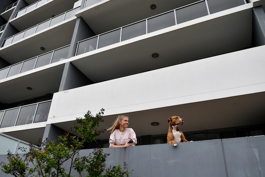 a woman standing on an apartment balcony with a dog