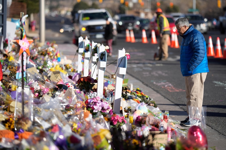 A lone visitor looks over the makeshift memorial near the scene of a shooting.