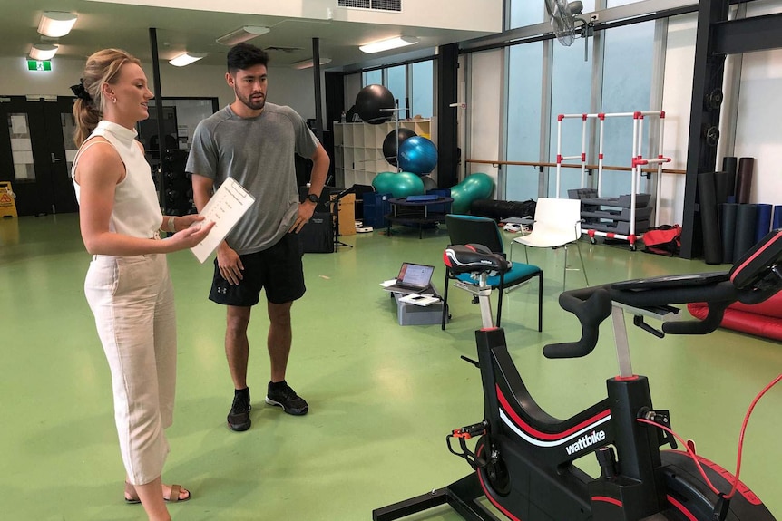 Researcher Suzy Russell, stands alongside a male athlete at a training facility in Brisbane