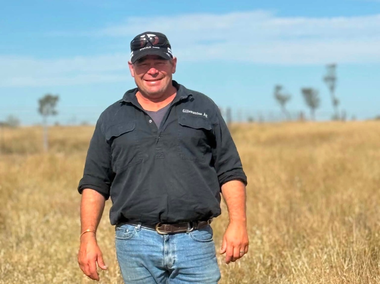 A farmer in a paddock smiling at the camera