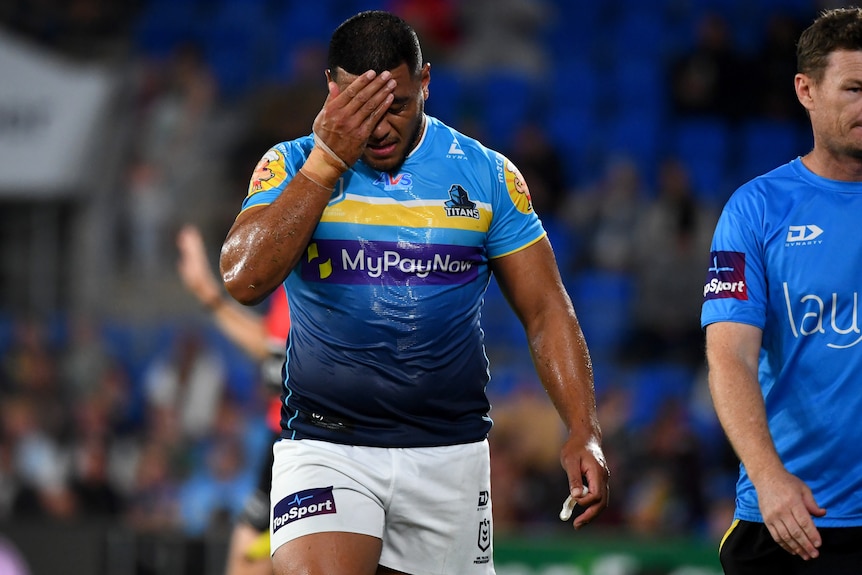 A Gold Coast Titans NRL player puts his right hand to his forehand after he was sent off against Warriors.
