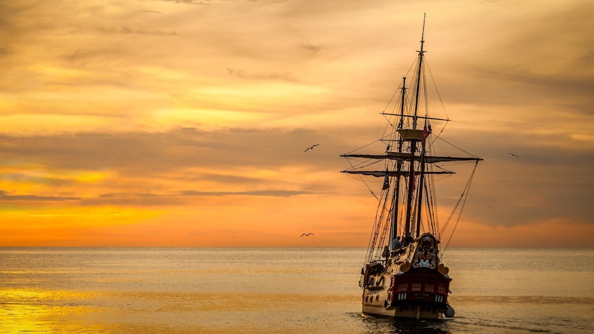 Old sailing boat on the ocean at sunset