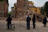 People look at a clock tower in Finale Emila which collapsed following an earthquake.