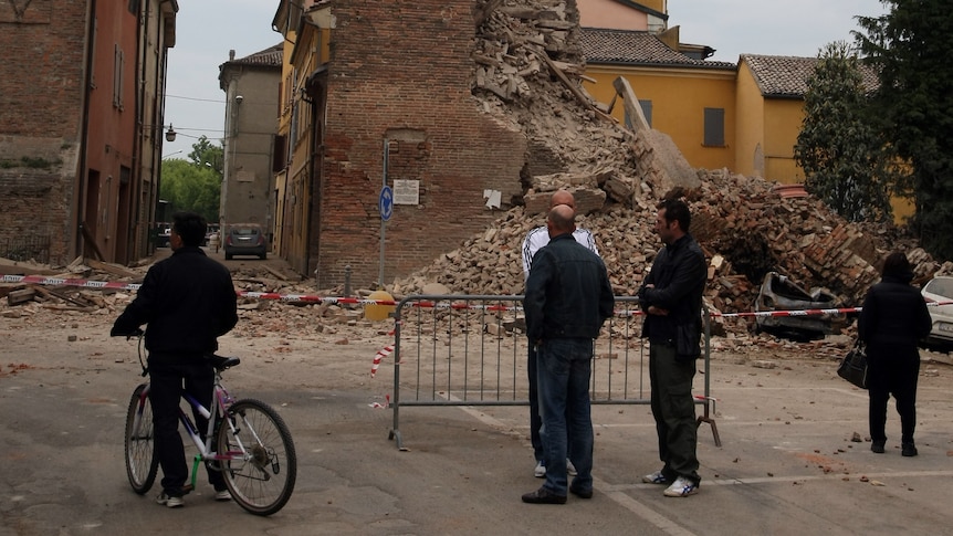 People look at a clock tower in Finale Emila which collapsed following an earthquake.