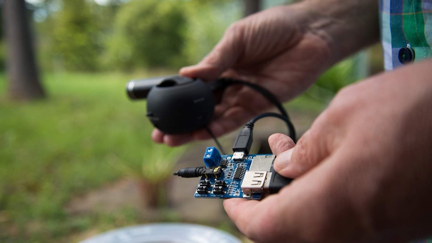 Professor Ritchie holds the components of the male mosquito lure - an Mp3 player, a speaker and a battery pack - in his hands.