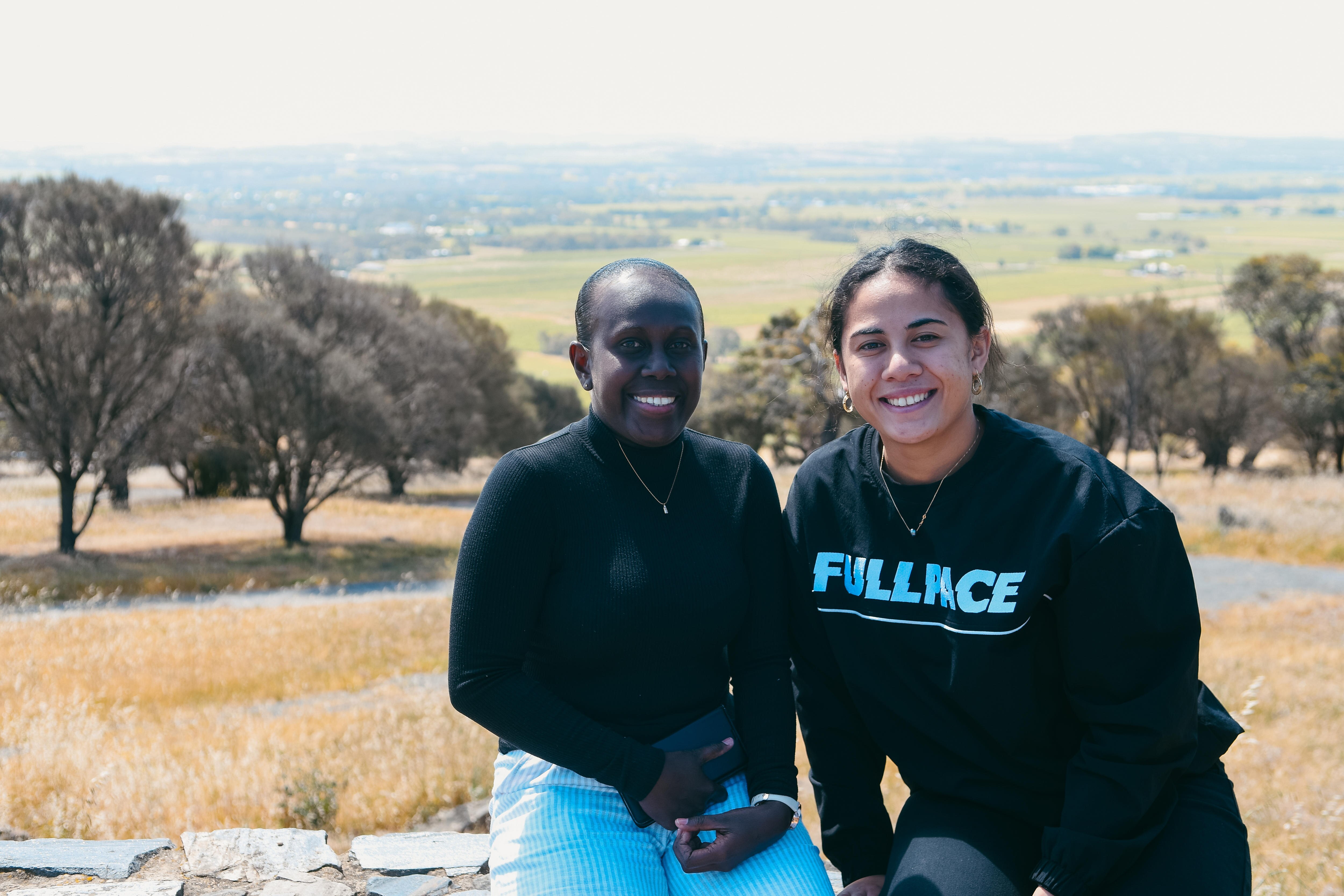 two women sit with a spectacular view across the Barossa Valley behind them