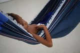 A Yanomami toddler lies on a hammock