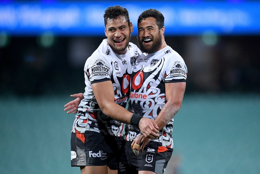 Two Warriors players embrace and smile as they celebrate a try against the Wests Tigers at the SCG in Sydney.