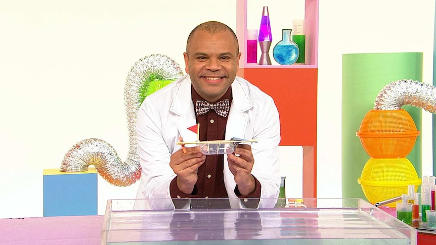 Luke on the Play School Science Time set wearing a lab coat holding a craft boat