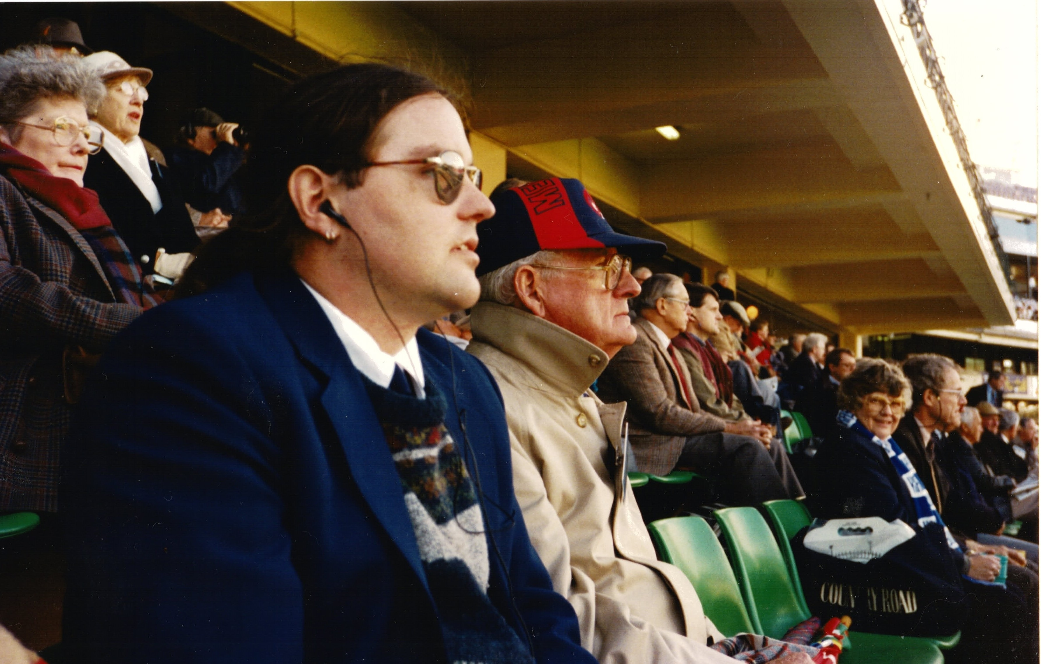 A young man and his father sit in a stadium.