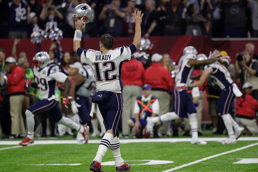 Tom Brady raises his helmet after winning Super Bowl LI