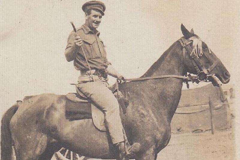 Black and white image of a soldier in his army uniform sits on his horse. 